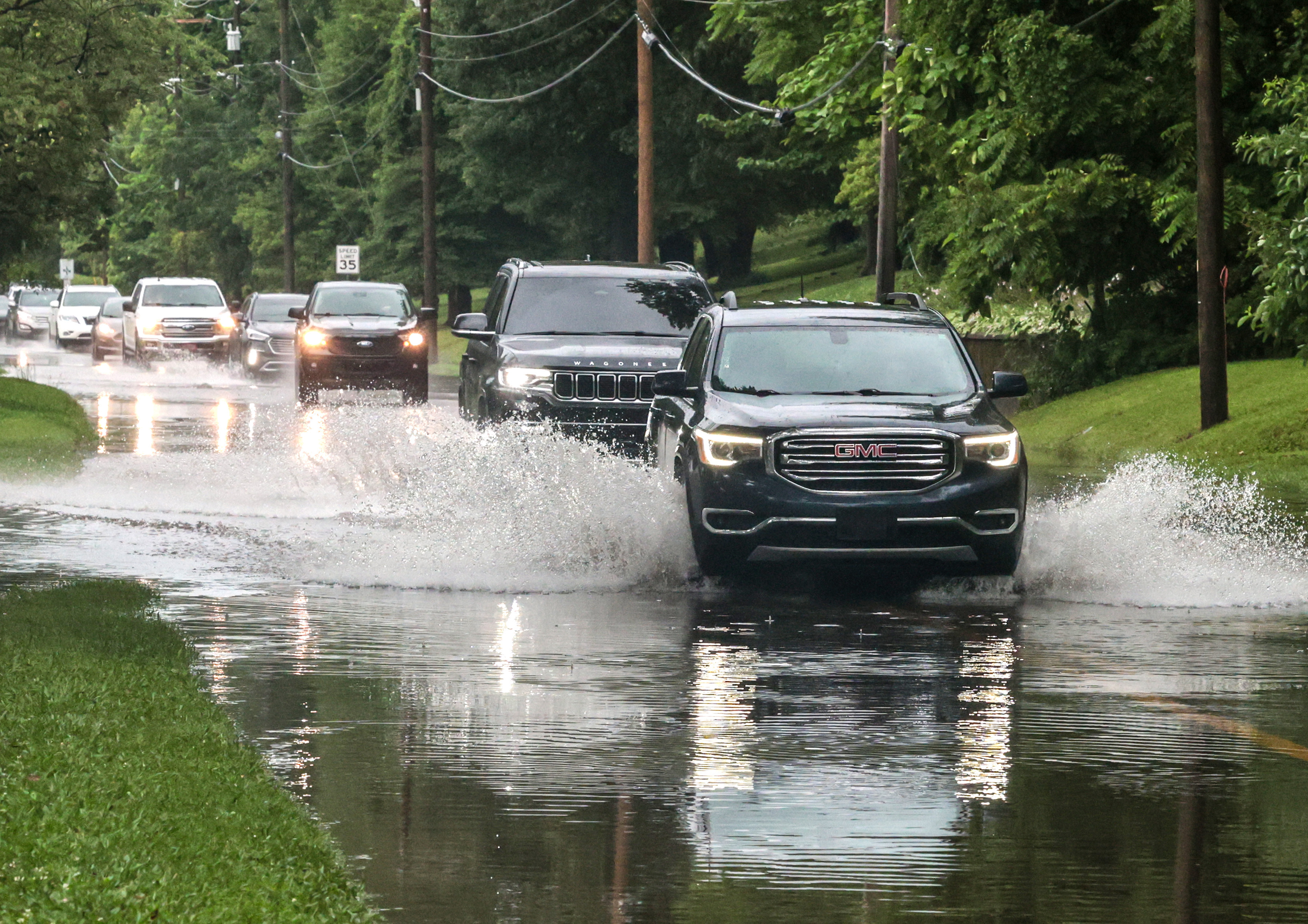 Drivers maneuver their vehicles through high water flooding West Parrish Avenue after a heavy rainfall